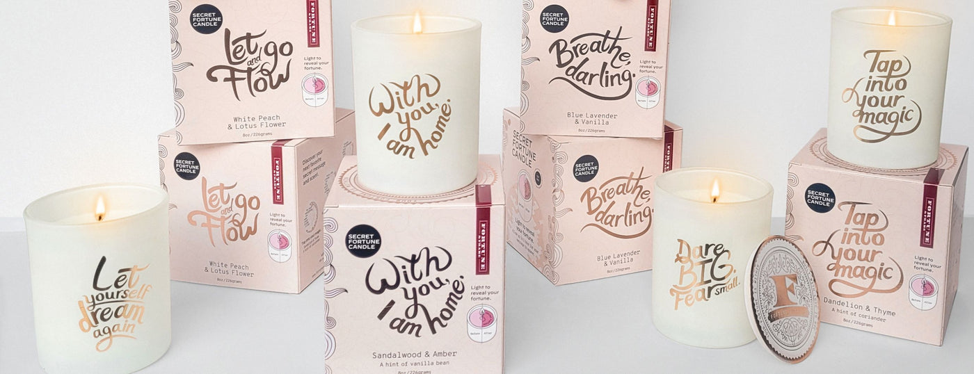 A stack of Fortune & Frame's Secret Fortune Candles and their packaging.