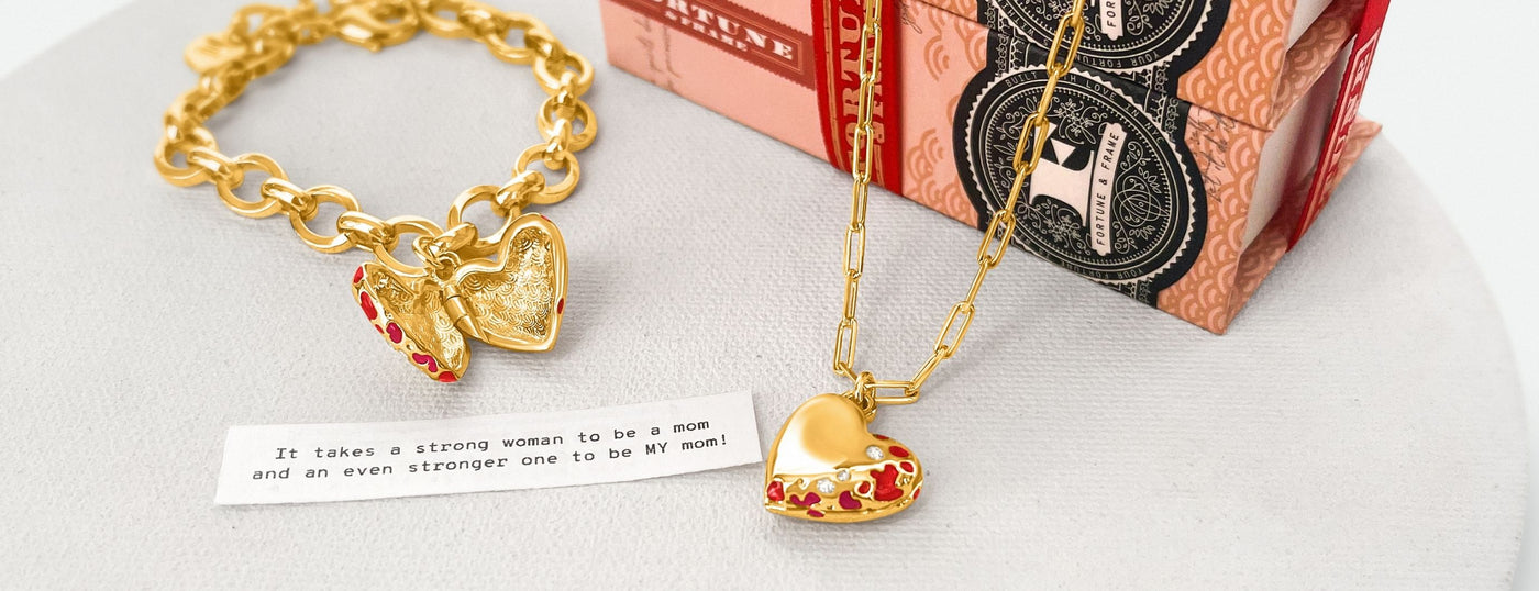 An open Jeweled Heart Bracelet and closed Jeweled Heart Locket shown with their signature storybook packaging and a fortune that reads "It takes a strong woman to be a mom and it takes a stronger woman to be MY mom." 