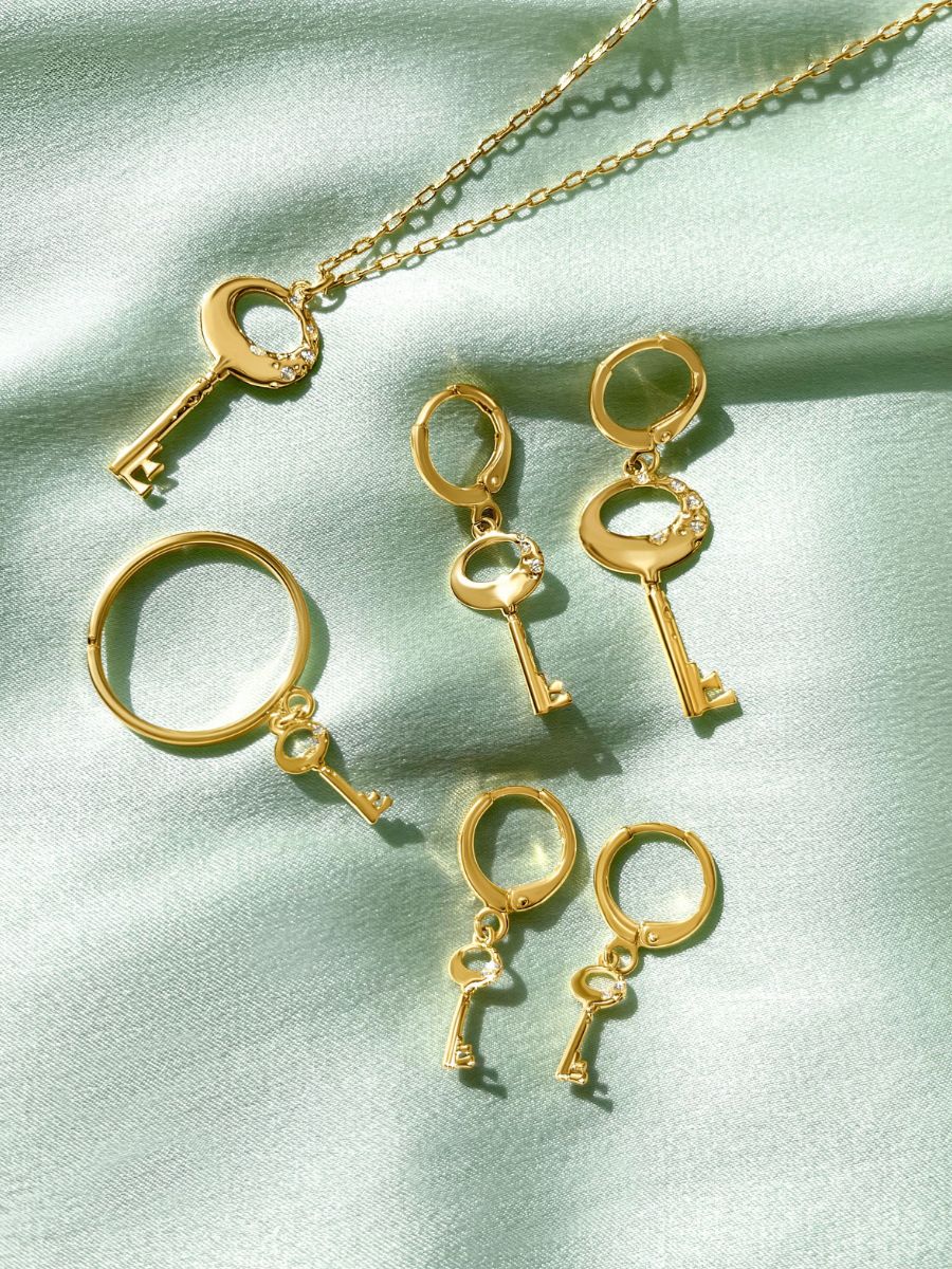 All of our Key Necklaces & Jewelry laid out over a green silk sheet.