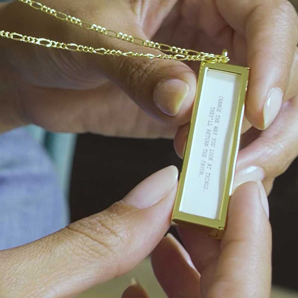 A video of a girl opening a gold envelope locket and looking at the fortune inside: "Change the way you look at things. They'll return the favor."