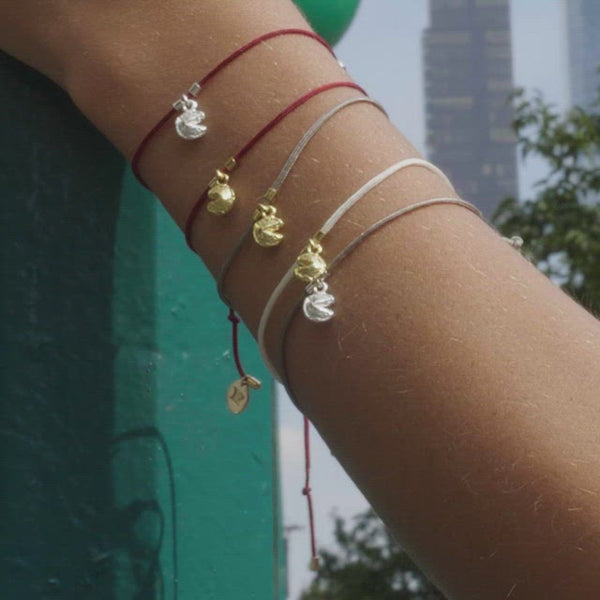 Video shows a models arm resting on the subway. The model is wearing 5 Fortune Cookie String Bracelets, all stacked on one arm. The wind is blowing, showing how the string moves gently in the breeze.